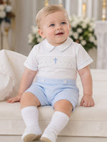 Carriage Boutique white cotton bobbie suit with blue smocking, cross detail, and light blue shorts for baby boys.